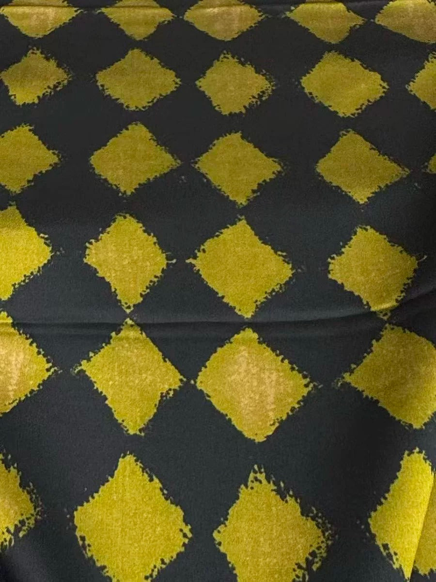 a close-up view of a fabric with a diamond pattern in black and gold colors. The diamonds are arranged in a diagonal pattern, creating a visually striking design.
