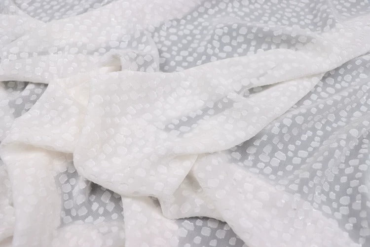 a close-up view of a white fabric with a pattern of small white dots or circles on it.
