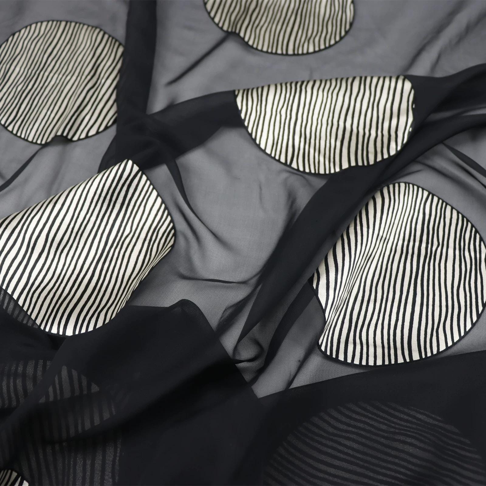 a close-up view of a fabric with a black and white striped pattern, featuring circular shapes with a striped design.