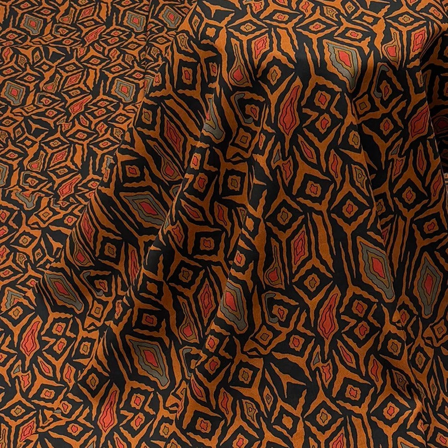 a close-up view of a fabric with a repeating pattern of orange and black diamond shapes. The pattern is intricate and detailed, with the diamonds varying in size and shape. The fabric appears to be made of a soft, textured material, and the overall composition suggests a high-quality, well-crafted textile product.