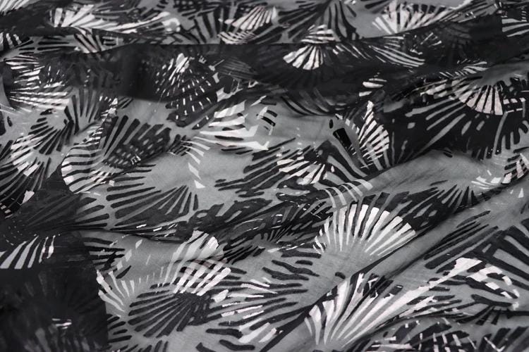a close-up view of a fabric with a repeating pattern of black and white lines, resembling a fan or a leaf-like design.