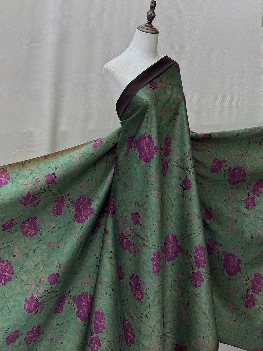 A mannequin wearing a green dress with a floral pattern in shades of purple and green.