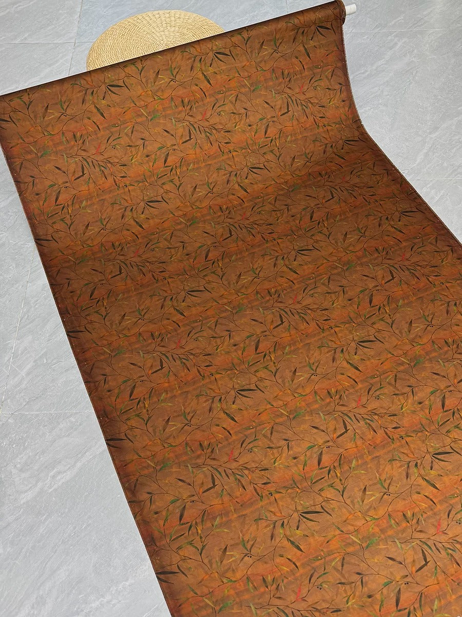 a roll of fabric with a repeating pattern of orange and green leaves.