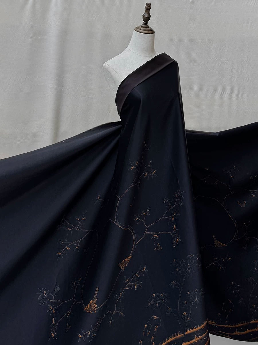 A mannequin wearing a black dress with a gold floral pattern.