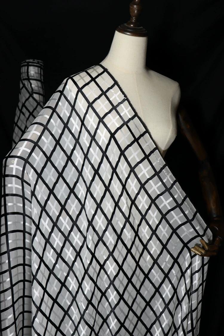 A mannequin wearing a white dress with a black and white checkered pattern.