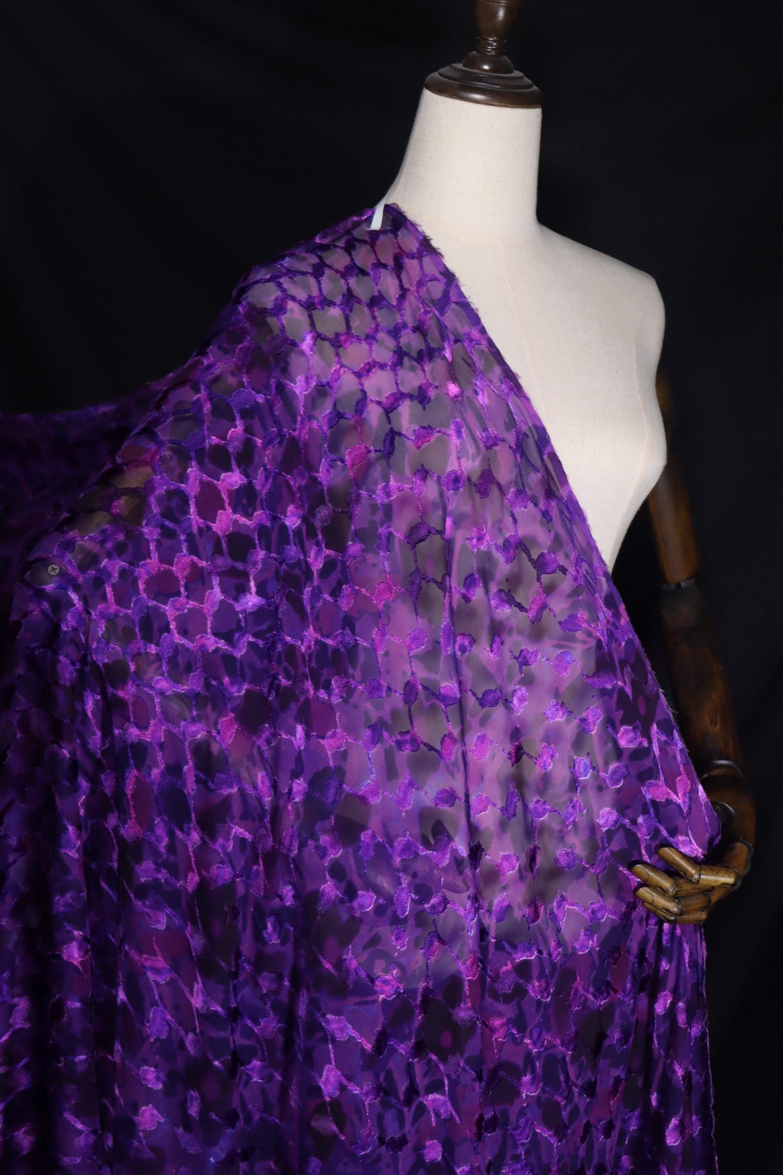 A mannequin wearing a purple and black patterned fabric draped over its body.