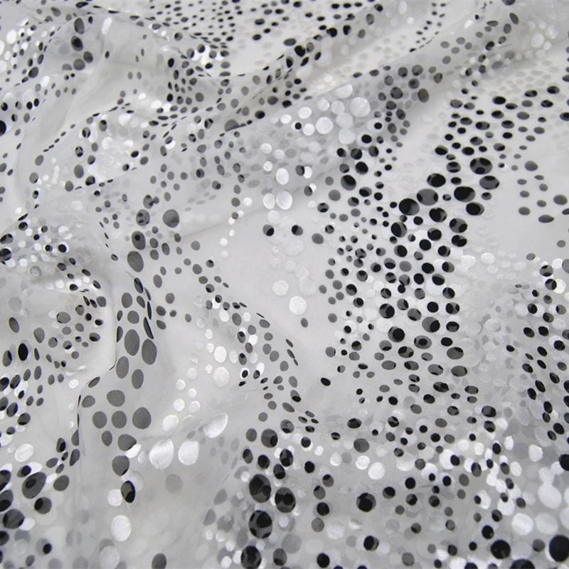 The image is a close-up of a fabric with a pattern of small black dots or circles on a white background.