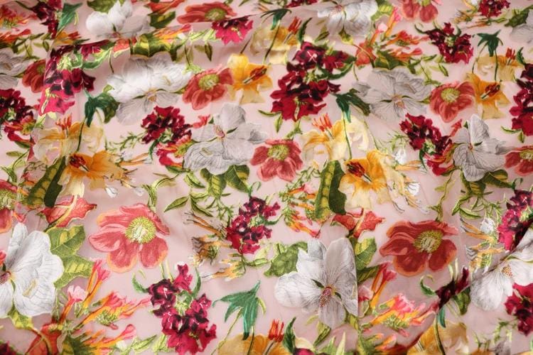 a close-up view of a fabric with a vibrant floral pattern. The fabric is adorned with a variety of colorful flowers, including red, white, yellow, and green, creating a visually striking and lively design. The flowers are arranged in a way that fills the entire fabric, showcasing the intricate details and patterns of each individual flower.