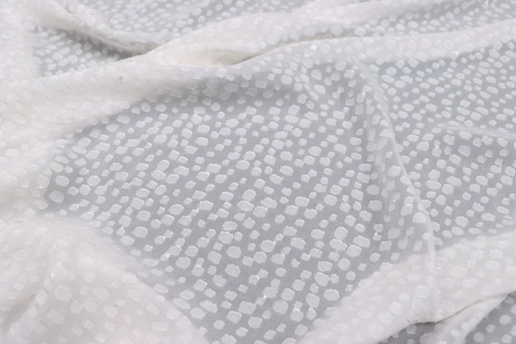 a close-up view of a white fabric with small white dots or circles on it, creating a textured and patterned appearance.