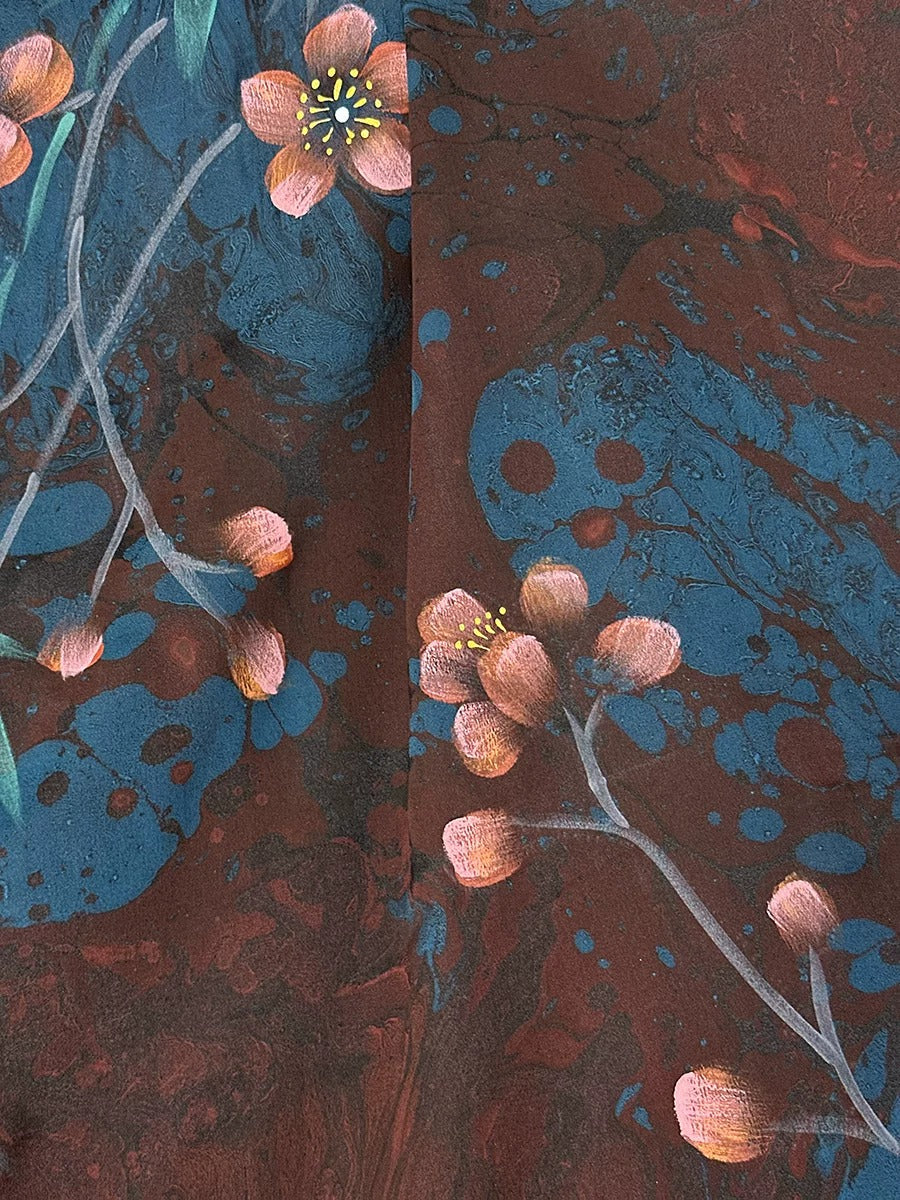a close-up view of a vibrant floral pattern, with delicate pink flowers and branches against a dark blue background. The flowers are the main focus, with some branches extending from the center of the image. The overall composition is visually striking and captures the beauty of nature.