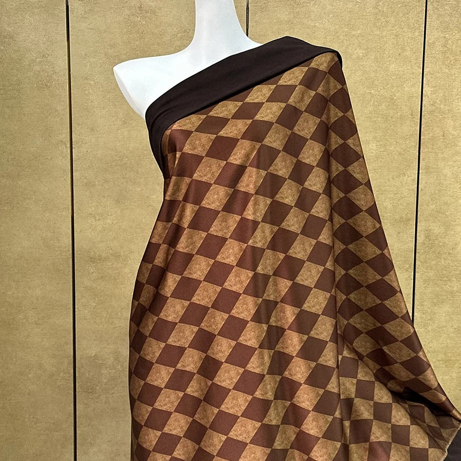 A mannequin wearing a brown and black checkered patterned dress with a black top.