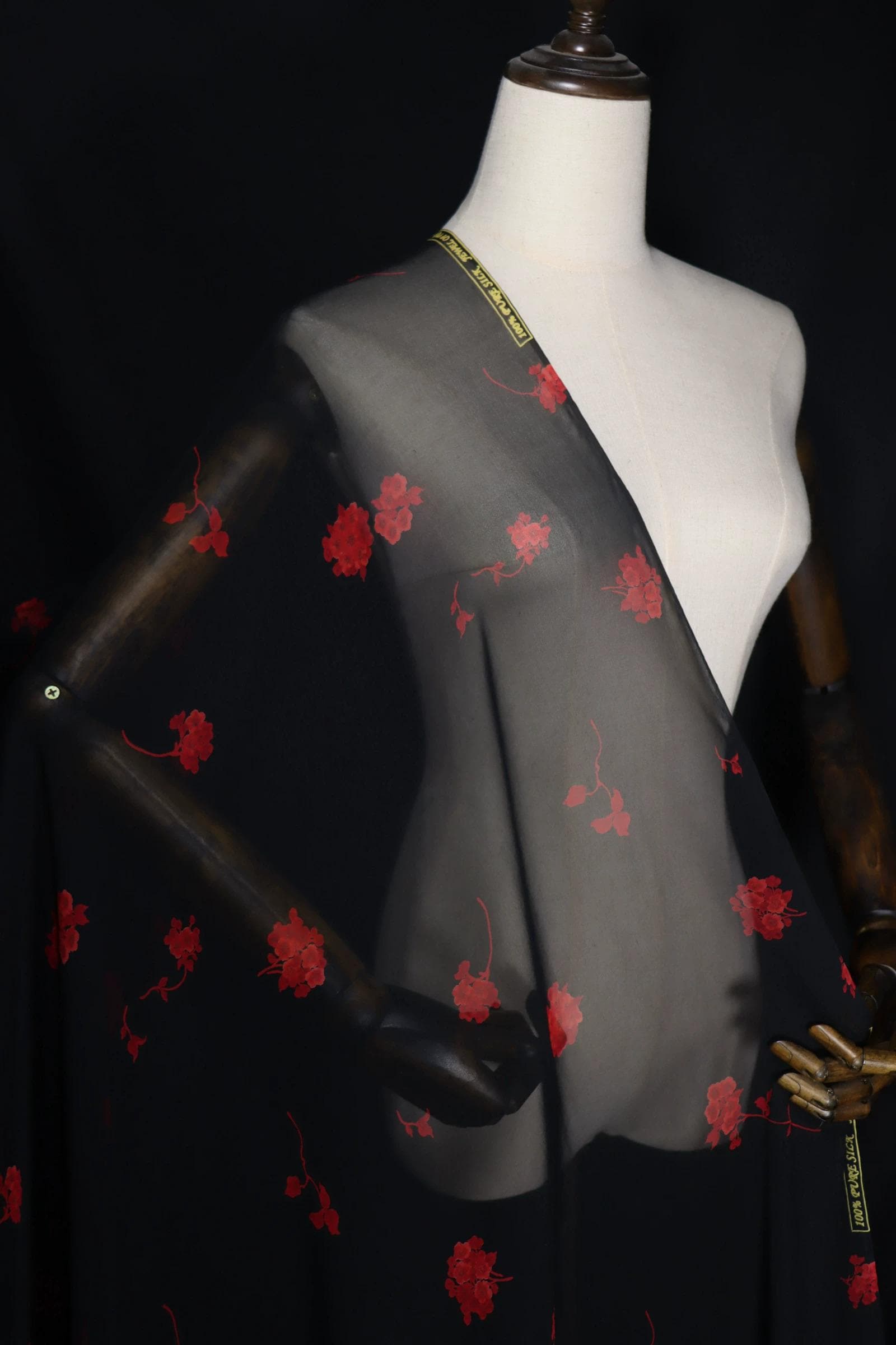 A mannequin wearing a black dress with red floral embroidery on the front.