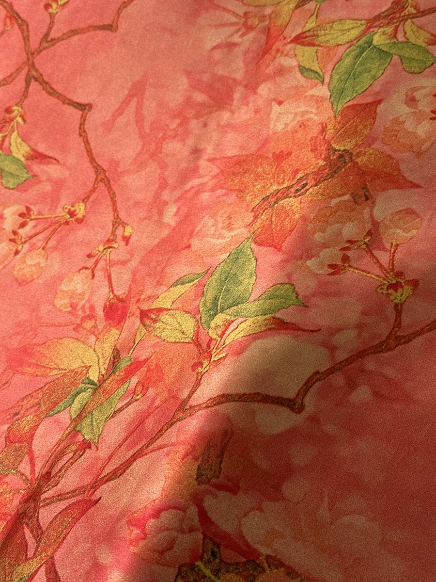 a close-up view of a fabric with a vibrant floral pattern in shades of pink and green. The pattern includes leaves and flowers, creating a visually appealing and intricate design.