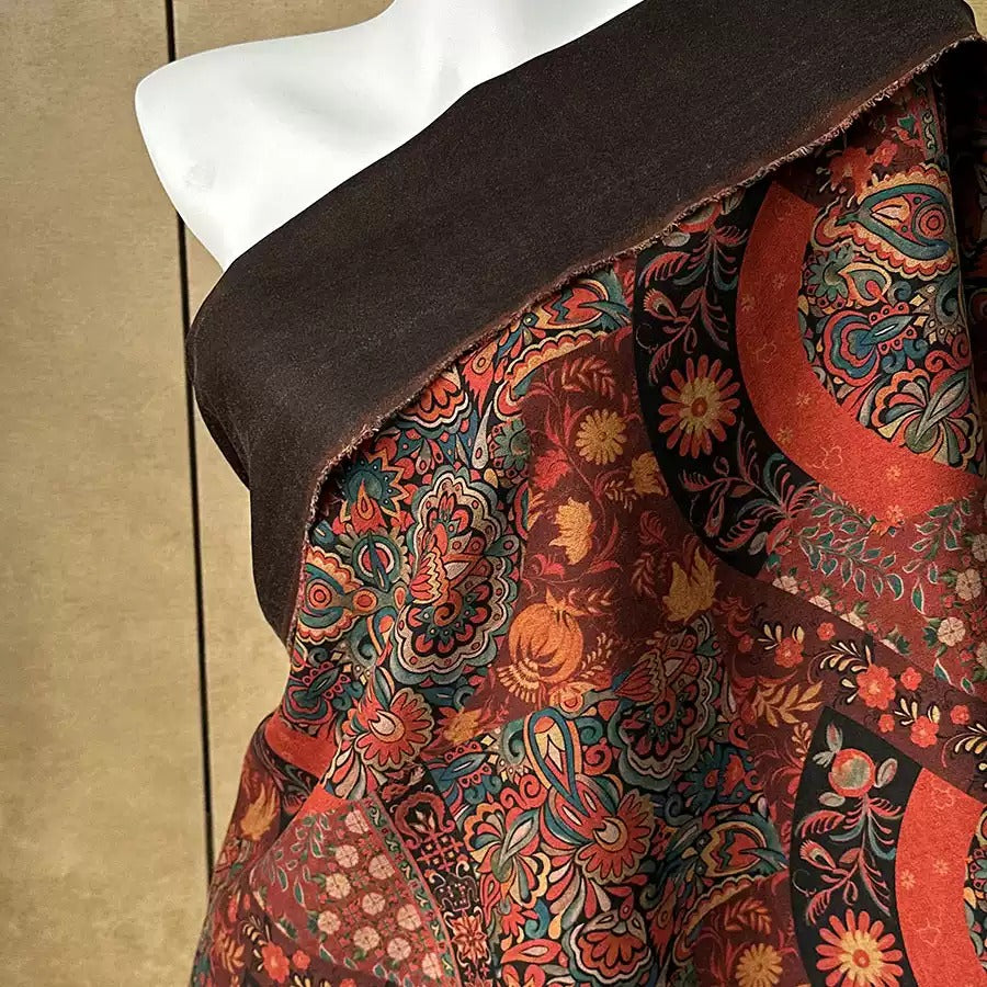 a mannequin wearing a colorful, patterned fabric with a dark brown trim.