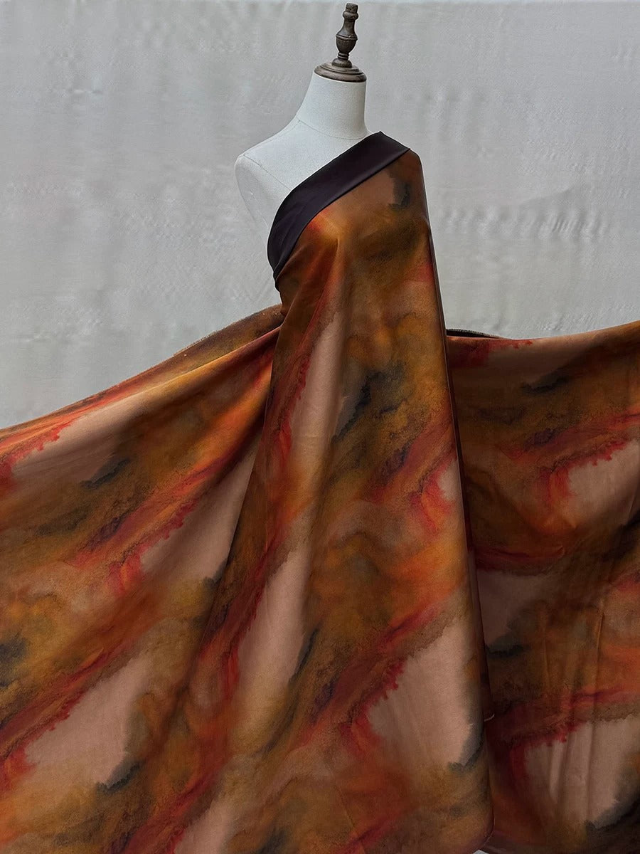 A mannequin wearing a long, flowing dress with a vibrant, abstract pattern in shades of orange, red, and brown.