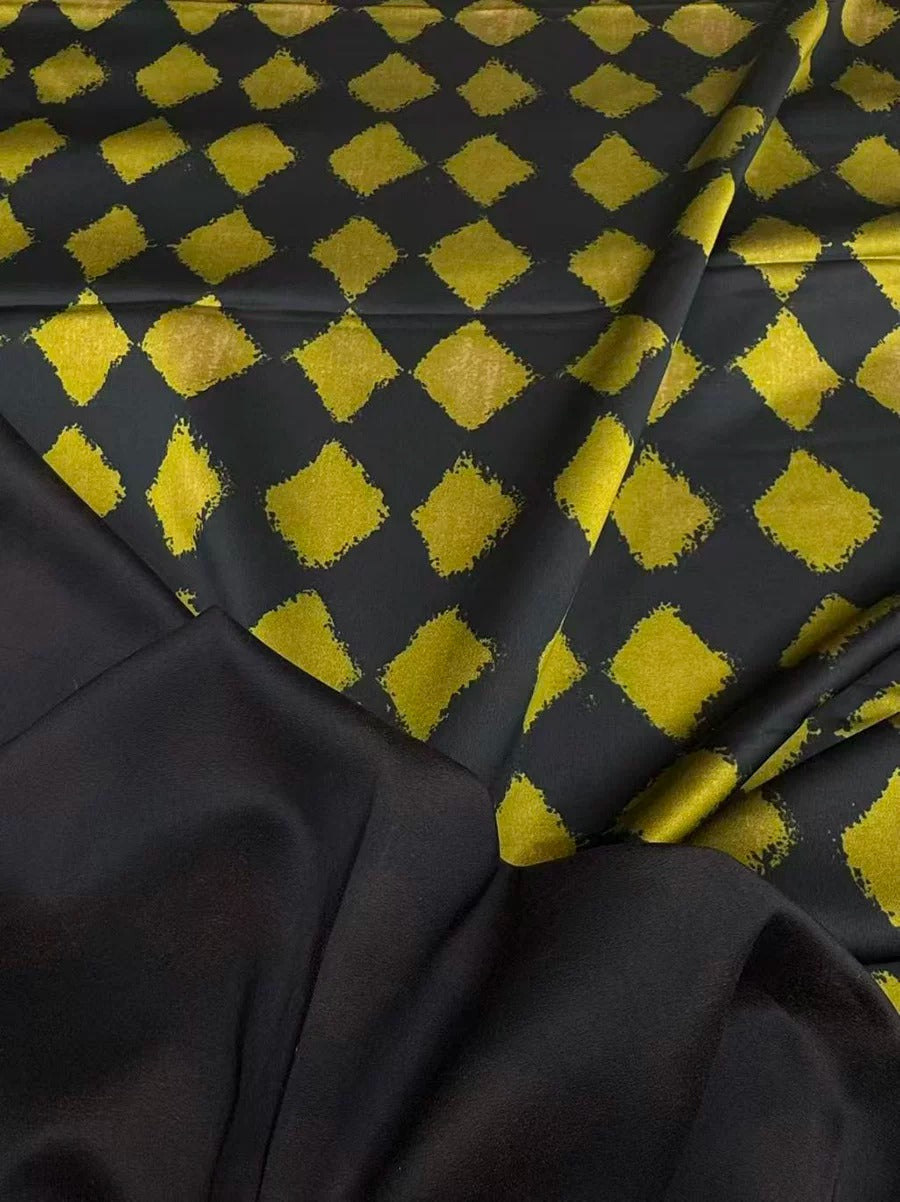 a close-up view of a fabric with a black and yellow diamond pattern. The fabric appears to be a blend of black and yellow colors, creating a visually striking contrast. The diamond pattern is visible on the fabric, adding a unique design element to the overall appearance.
