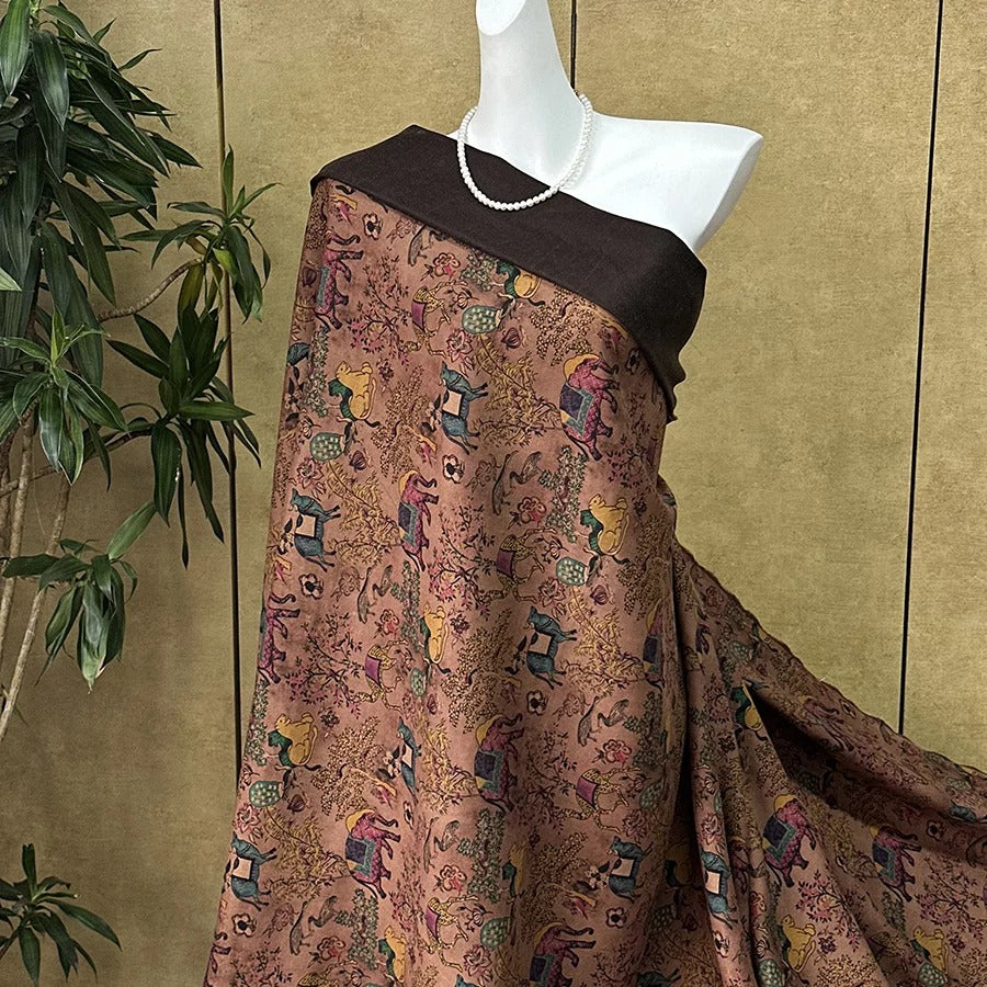 A mannequin wearing a brown and pink patterned dress with a black top, displayed against a beige wall with a plant in the background.