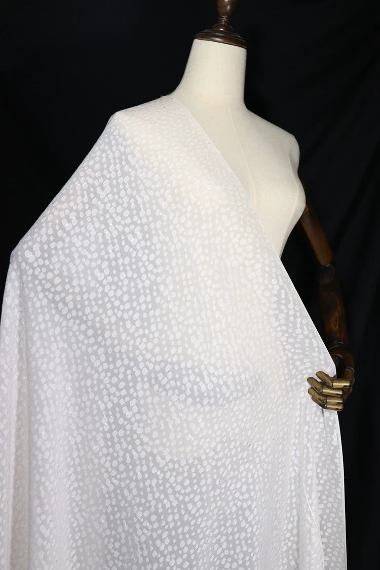 A mannequin wearing a white fabric with a polka dot pattern.