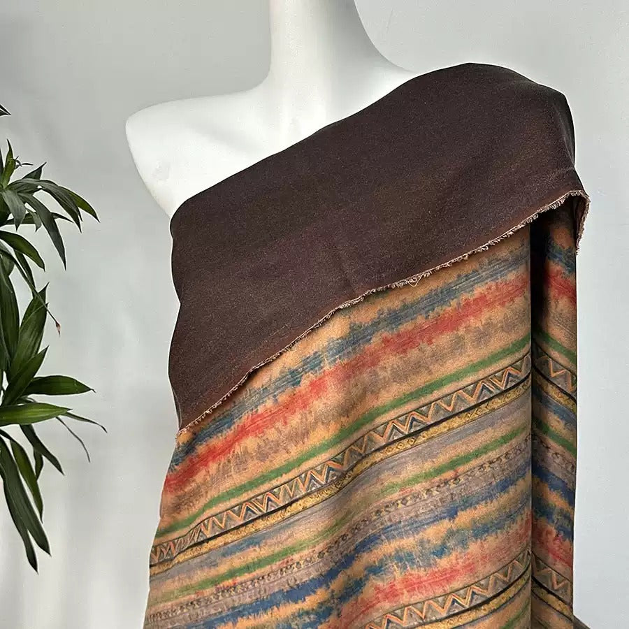 A mannequin wearing a brown shawl with a colorful, patterned fabric draped over it.