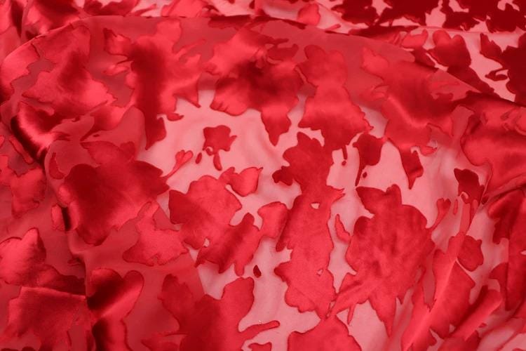 The image is a close-up of a fabric with a red floral pattern.