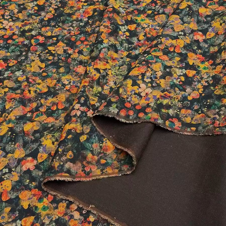 a close-up view of a fabric with a vibrant floral print in shades of orange, yellow, and green. The fabric appears to be a dark-colored material, possibly a dark-colored cotton or linen, with a contrasting background.