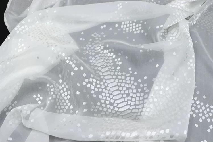 a close-up view of a white fabric with a pattern of small white squares or diamonds, creating a textured and visually interesting surface.