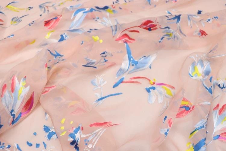 a close-up view of a fabric with a floral pattern in various colors, including pink, blue, and yellow.