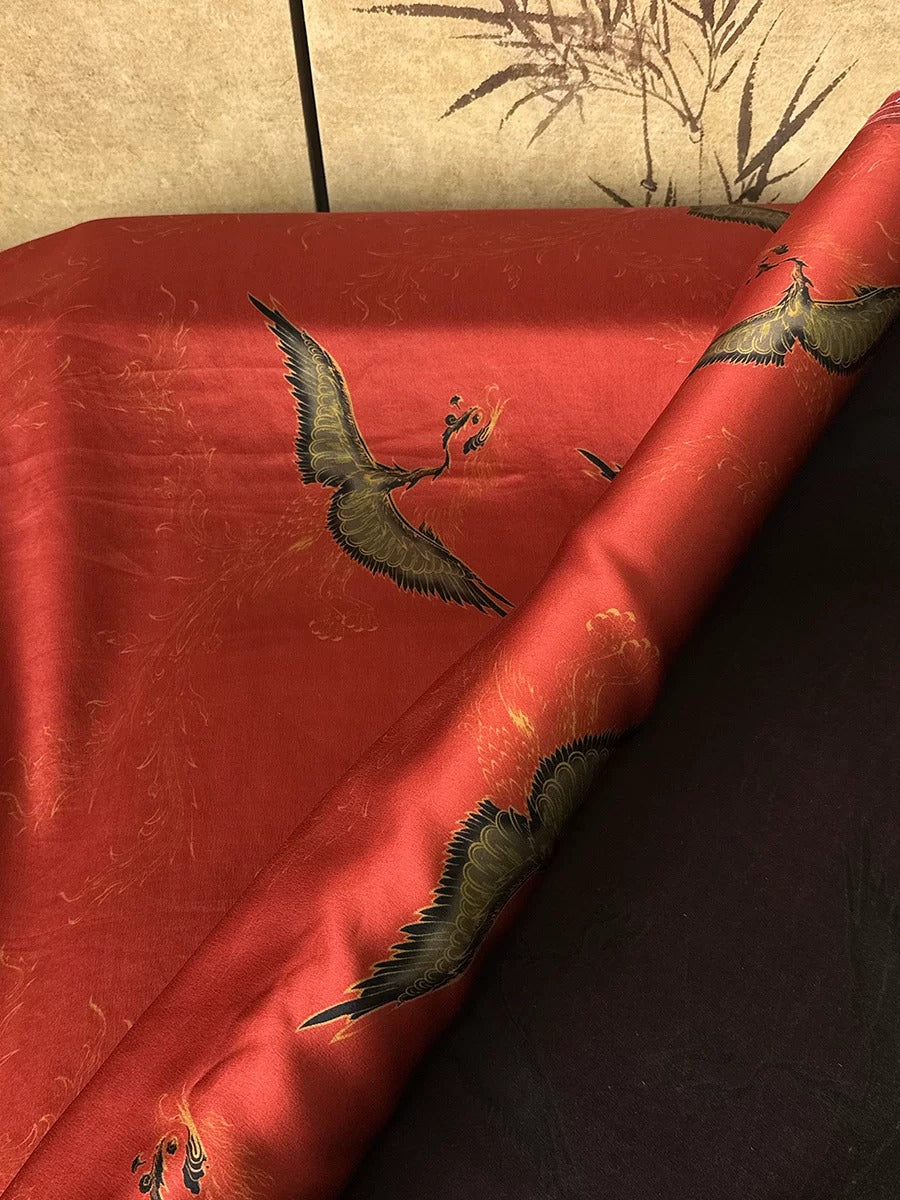 a red fabric with a black and gold bird design, including a crane, on it.