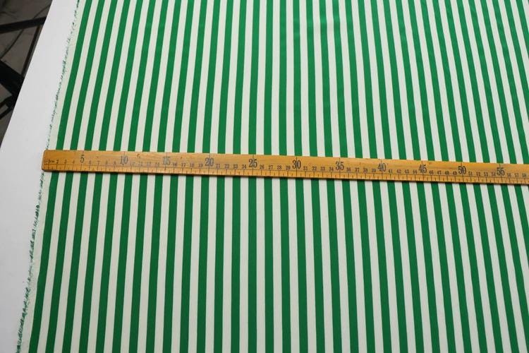a close-up view of a green and white striped fabric, with a ruler placed across it to measure the length of the fabric.