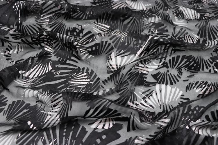 a close-up view of a fabric with a black and white abstract pattern, featuring various shapes and designs.