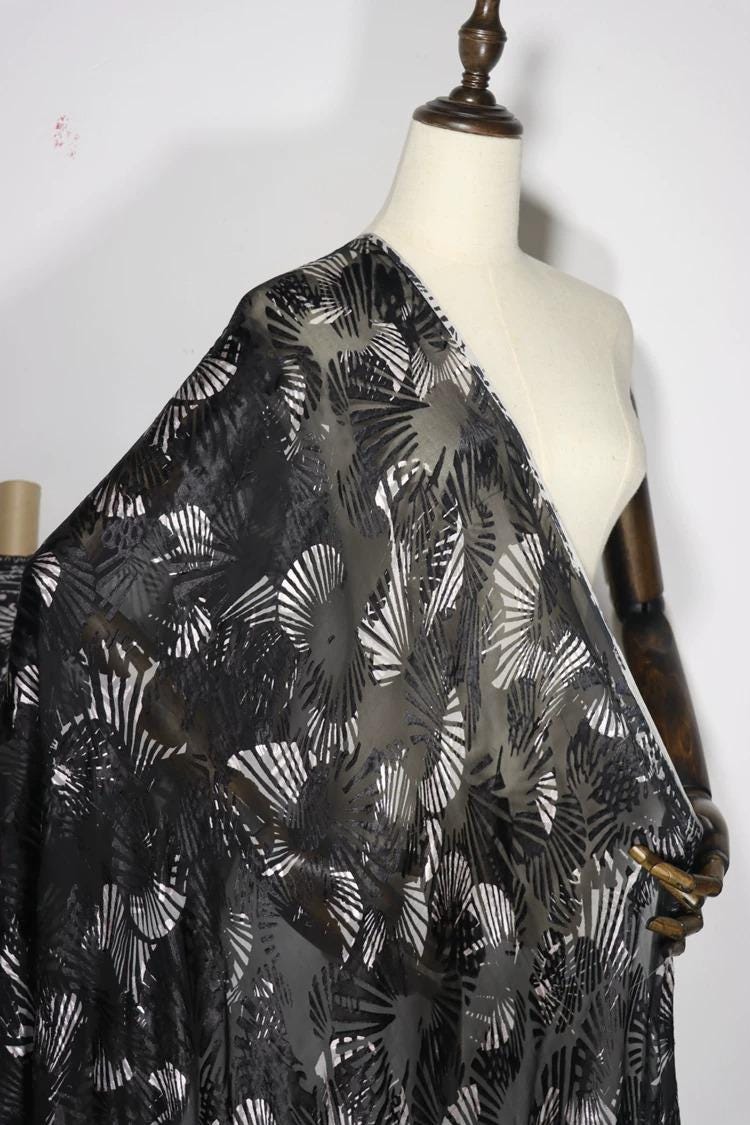 A mannequin wearing a black and white patterned fabric draped over it.