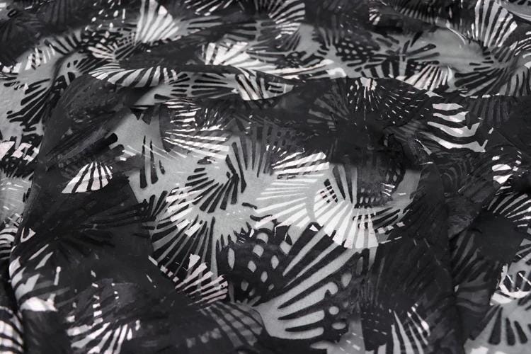 The image is a close-up view of a fabric with a black and white pattern, featuring a repeating design of black and white lines and shapes.