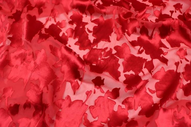 The image is a close-up of a fabric with a red floral pattern.