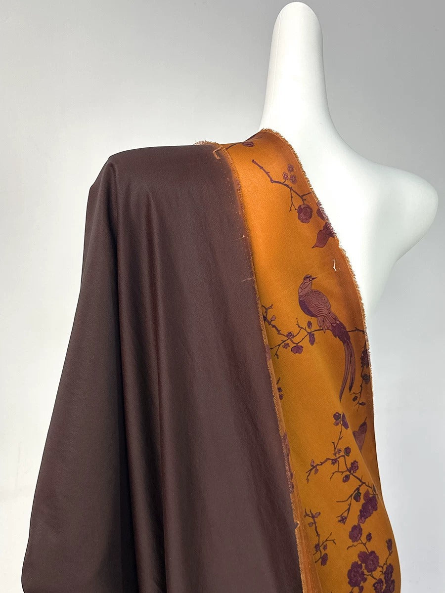 A mannequin wearing a brown and orange fabric with a bird design.