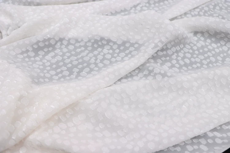 a close-up view of a white fabric with a pattern of small white dots or circles on it.