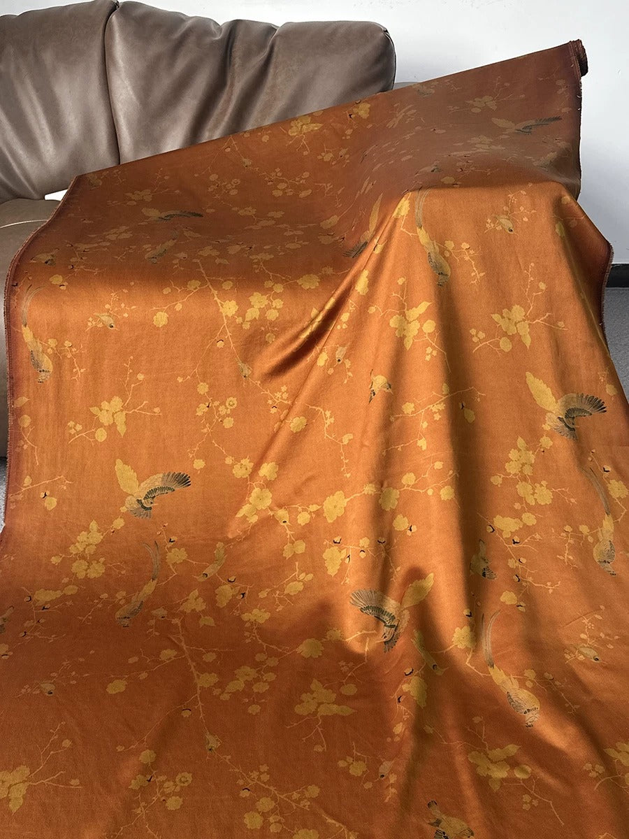 a large orange fabric with a floral pattern, folded and draped over a couch.