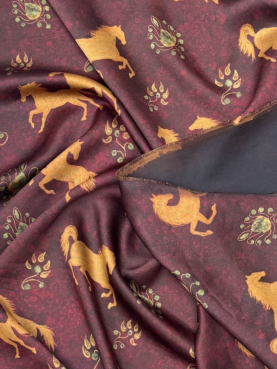 a close-up view of a fabric with a repeating pattern of gold horses against a burgundy background.