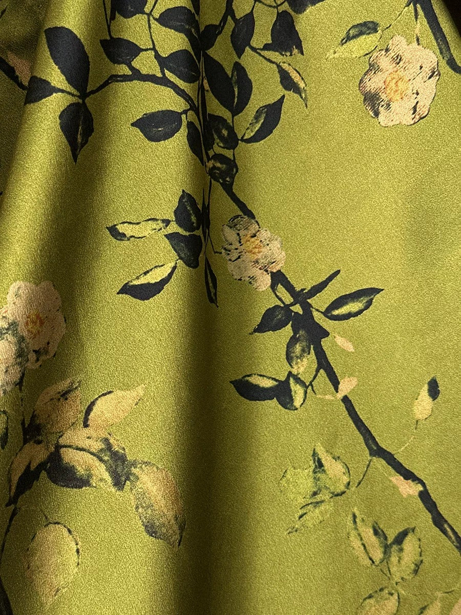a close-up view of a fabric with a floral pattern, featuring green and black colors.