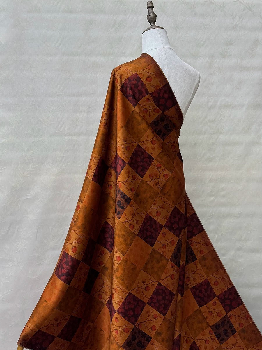 A mannequin wearing a dress with a vibrant, patterned fabric featuring a mix of orange and burgundy colors.