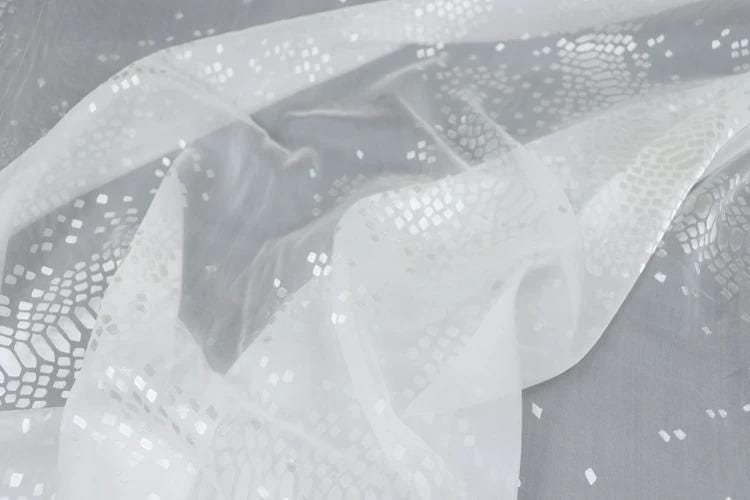 a close-up view of a white fabric with a pattern of small white dots or squares, creating a textured and visually interesting appearance.