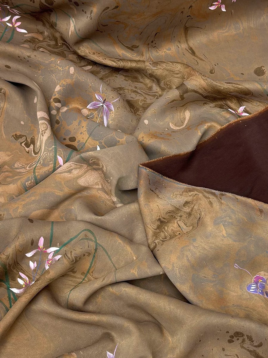 The image is a close-up view of a fabric with a floral pattern, featuring a mix of brown, green, and purple colors.