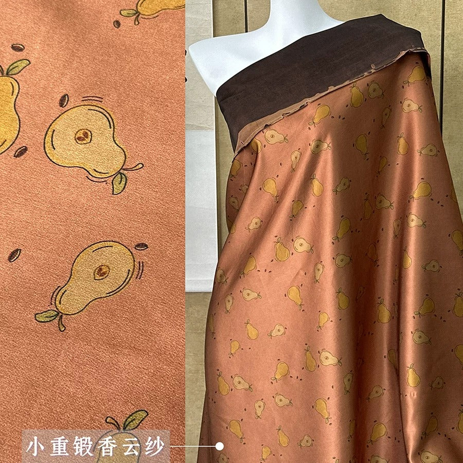 a mannequin wearing a brown and orange patterned fabric with a repeating design of pears.