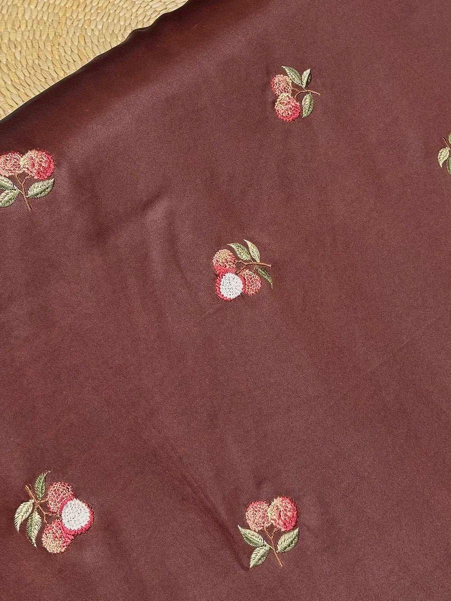 a close-up view of a brown fabric with small red flowers embroidered on it.