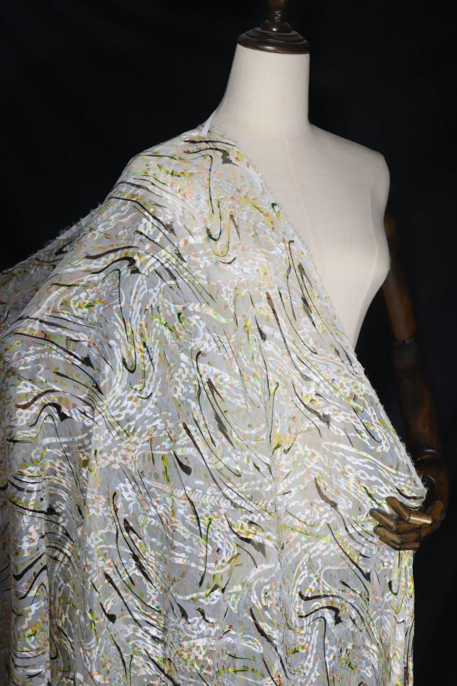 A mannequin wearing a white dress with a patterned fabric draped over it.