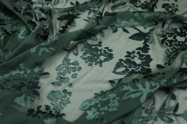 a close-up view of a fabric with a floral pattern, featuring various shades of green and black.