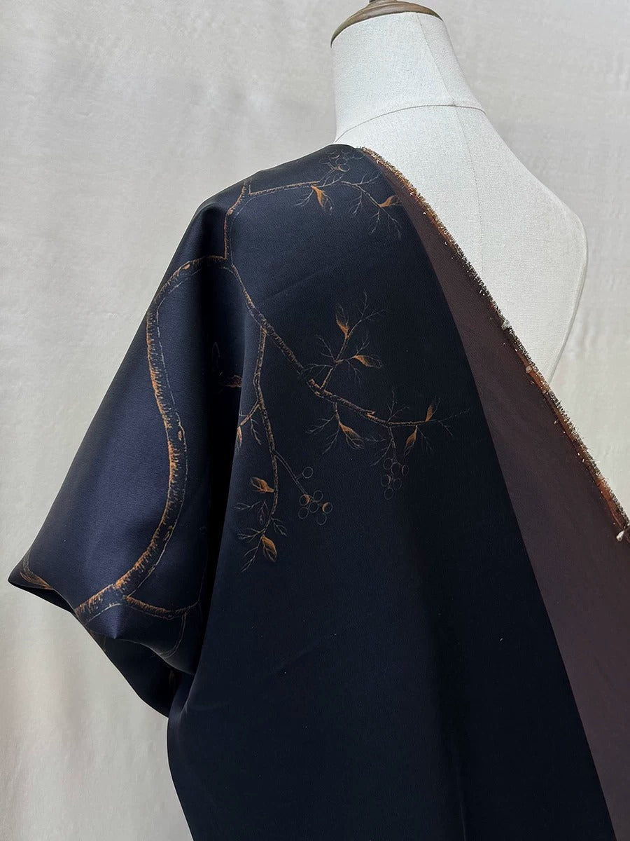 A mannequin wearing a dark blue dress with a gold leaf design on the sleeve.