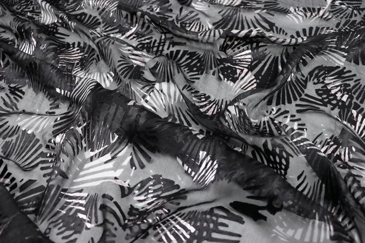 The image is a close-up view of a fabric with a black and white abstract pattern, featuring a repeating design of black and white lines and shapes.