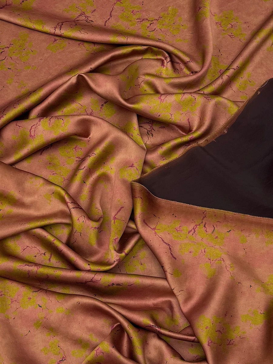 a close-up view of a fabric with a floral pattern in shades of pink and yellow. The fabric appears to be crumpled and wrinkled, giving it a textured and soft appearance.