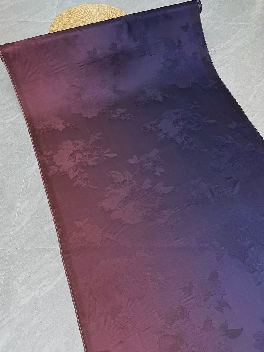 a piece of fabric with a floral pattern in shades of purple and blue, laid out on a gray surface.