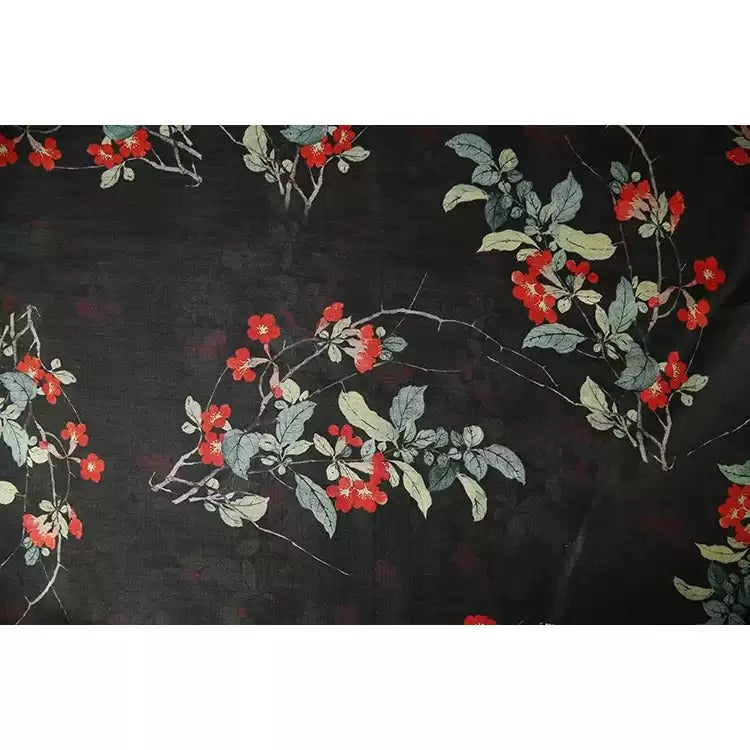 a close-up view of a black fabric adorned with a floral pattern of red flowers and green leaves.